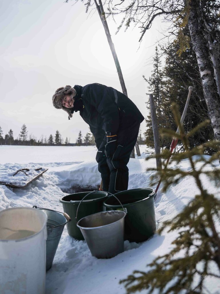 Husky Tour in Finnisch Lappland Wasser schöpfen aus einem Brunnen